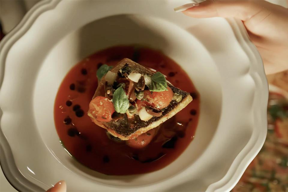 Fish dish in tomato broth served at Claudie restaurant in Miami